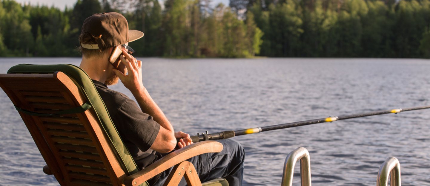 mies kalastaa laiturilla ja puhuu pihelimeen